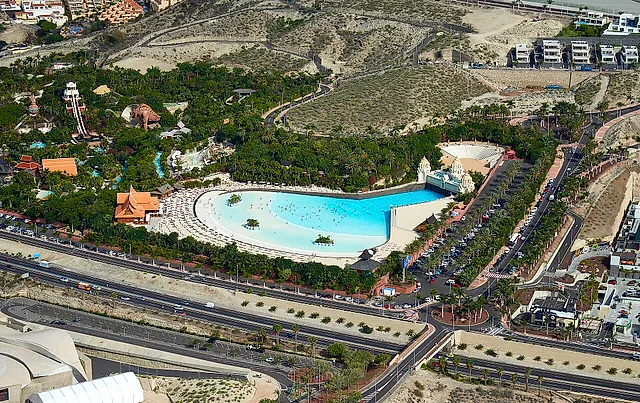 Veduta aerea di Siam Park con la grande piscina a onde circondata da giardini e la strada sottostante